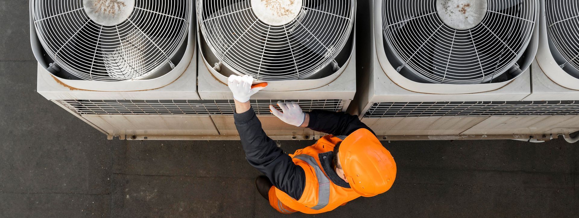 An aerial view of a man working on an air conditioner.