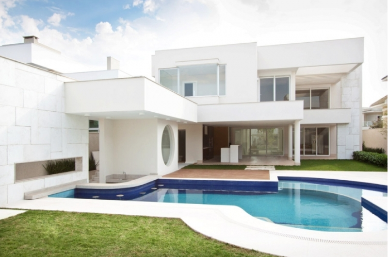 Casa branca moderna com piscina e gramado.