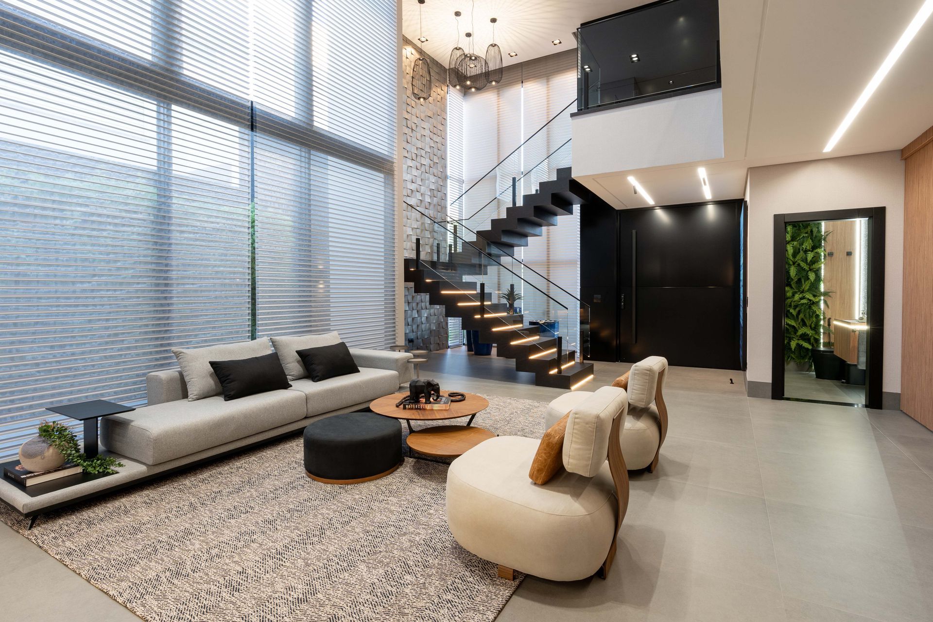 Sala de estar moderna com janelas grandes, escada e área de estar.