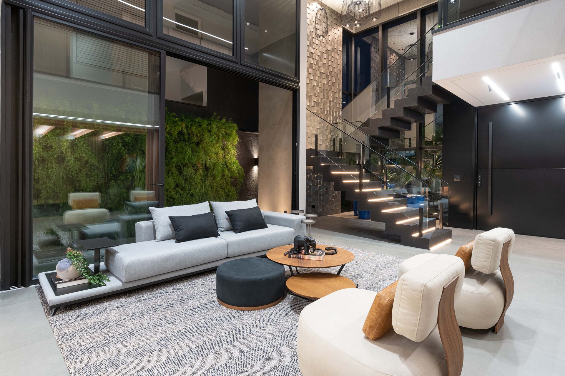 Sala de estar moderna com sofá cinza, mesas de centro de madeira e escada em espiral.