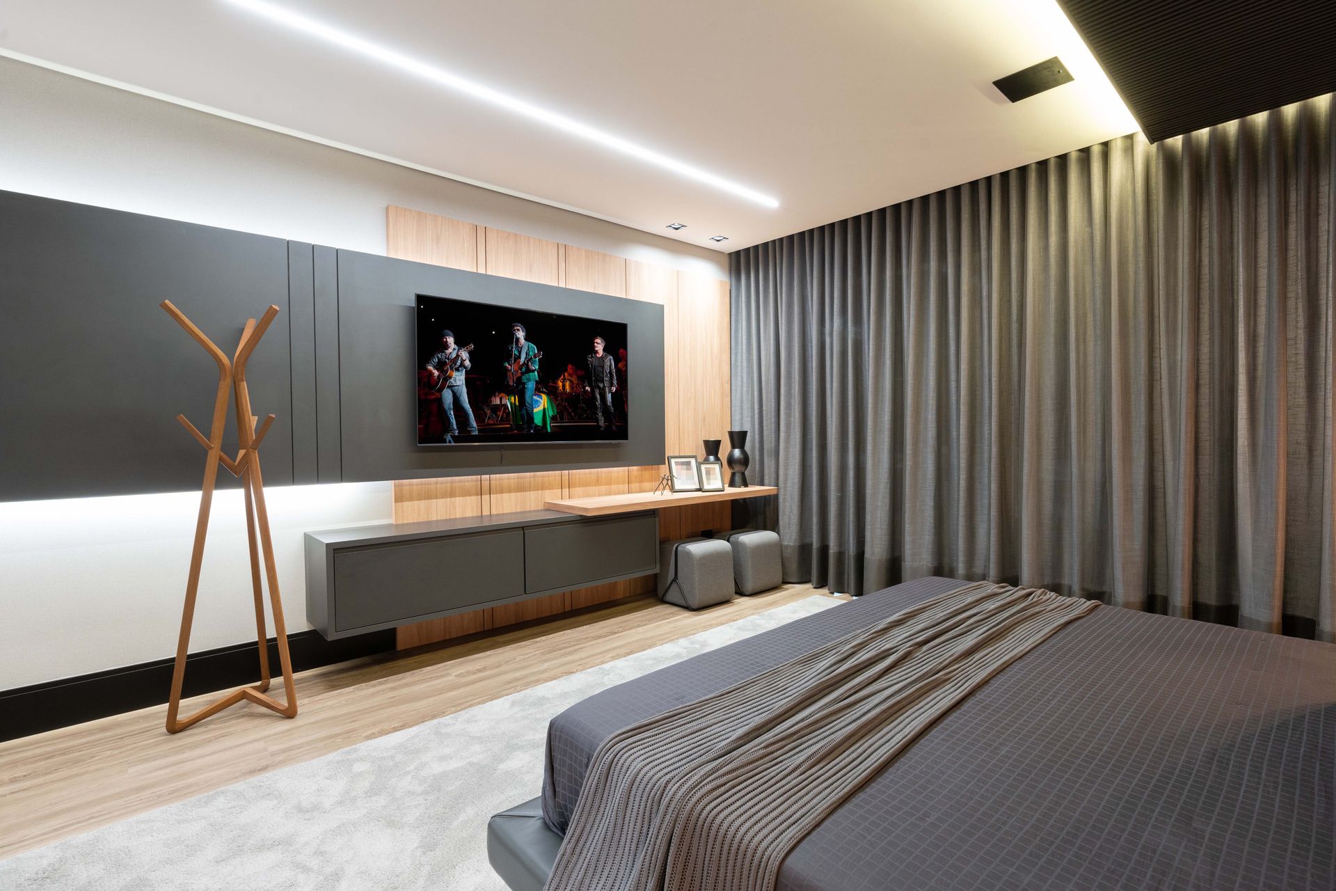 Quarto moderno com cama cinza, TV em uma parede cinza escura e longas cortinas cinza.