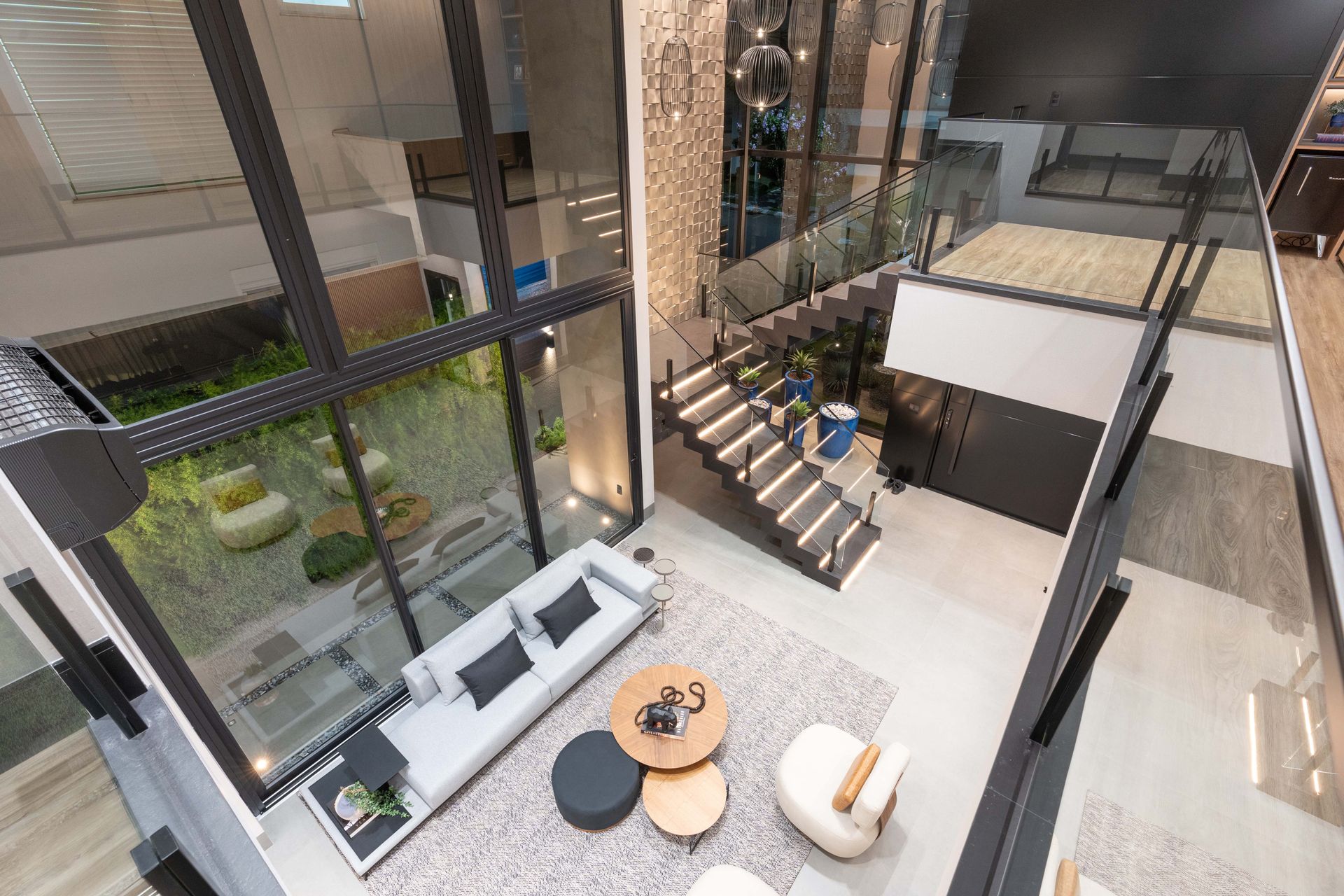 Sala de estar moderna de dois andares com janelas amplas com vista para o jardim. Possui assentos, escadas e mezanino.