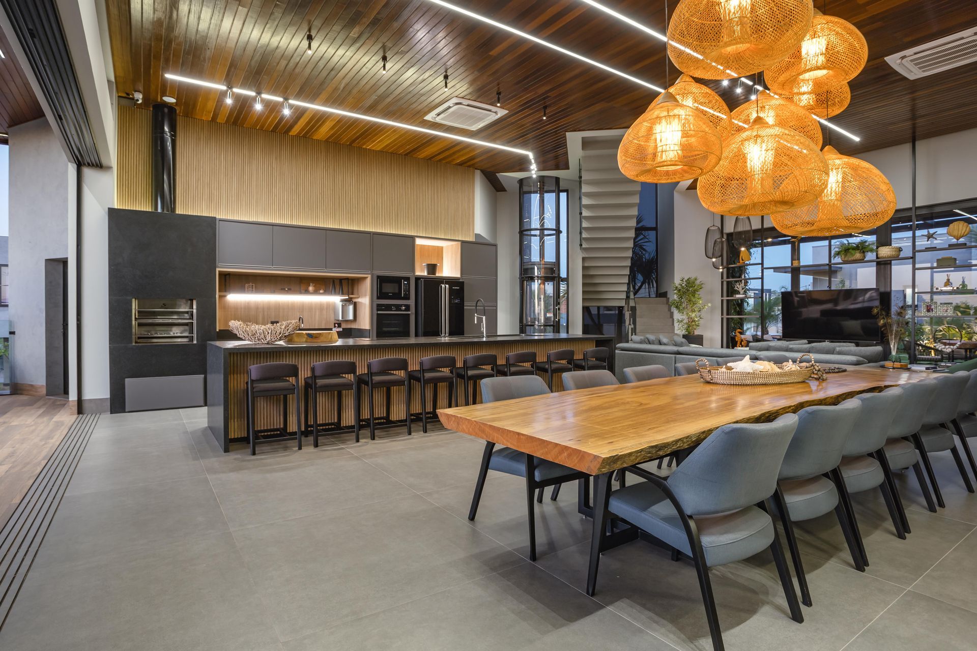 Cozinha moderna e espaçosa com uma longa mesa de jantar, bar e um lustre pendurado.