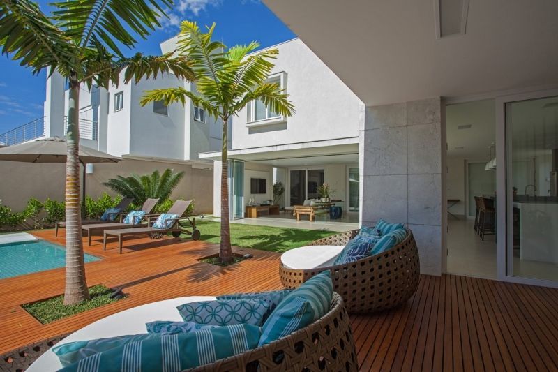 Pátio com piscina, espreguiçadeiras, palmeiras e moderna casa branca.