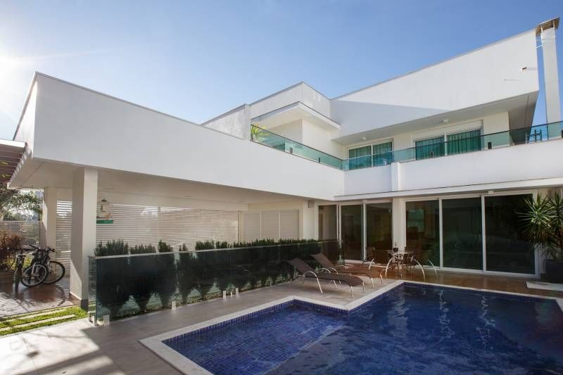 Casa branca moderna com piscina, móveis de jardim e uma bicicleta. Céu azul.