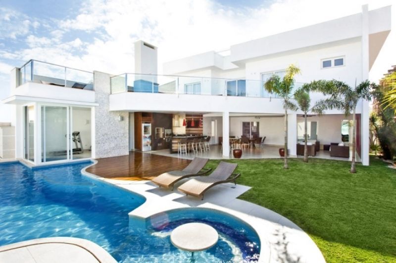 Casa branca moderna com piscina e espreguiçadeiras.