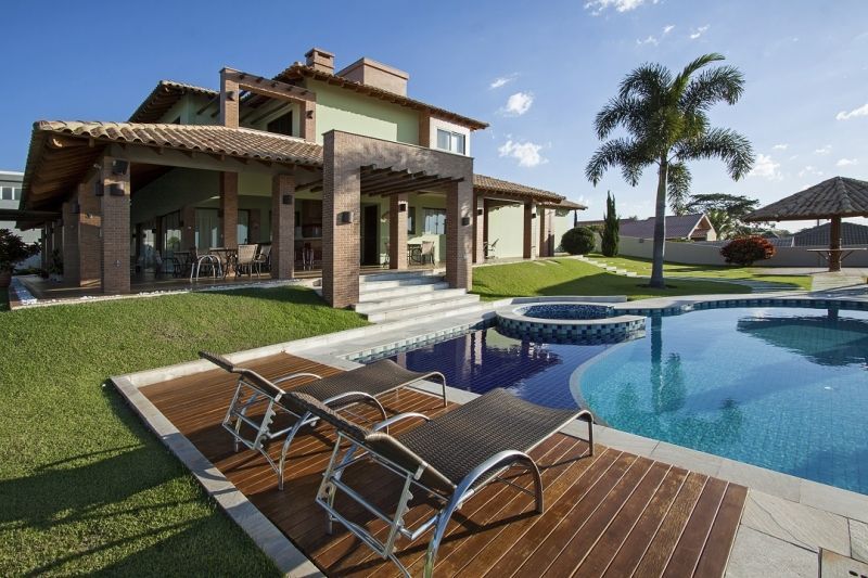 Casa luxuosa com piscina e espreguiçadeiras em um dia ensolarado.