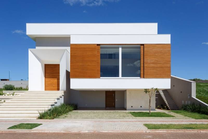 Casa branca moderna com detalhes em madeira e degraus que levam à porta da frente.