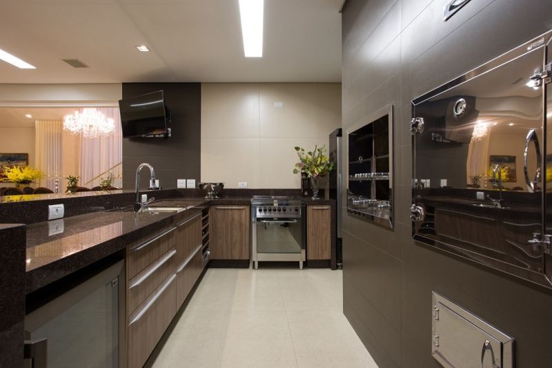 Cozinha moderna com armários marrom escuro, eletrodomésticos de aço inoxidável e paredes bege.