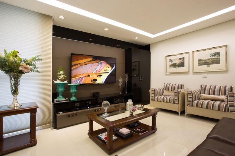 Sala de estar com TV, parede com detalhes em marrom, área de estar e arte.