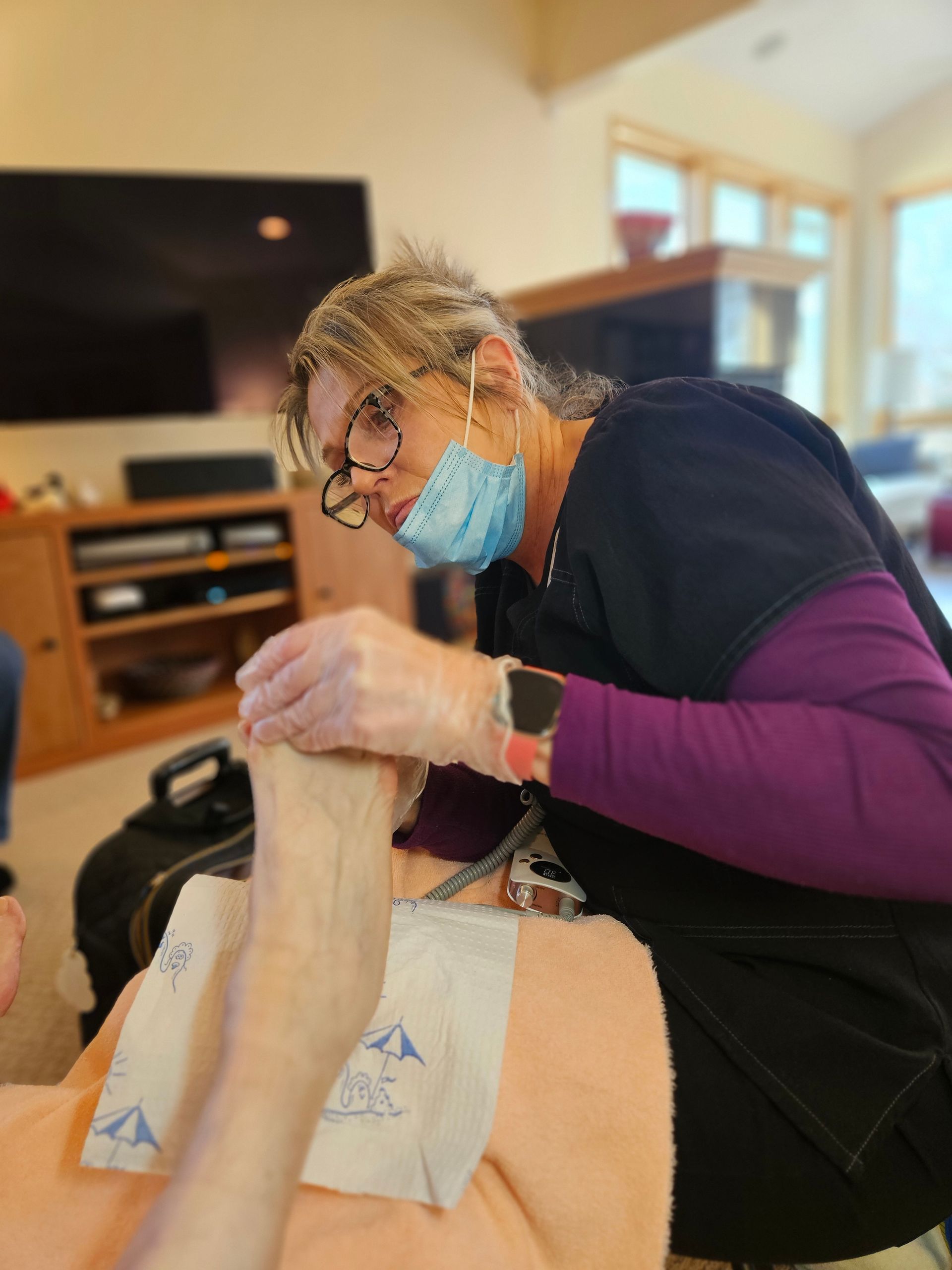A healthcare professional holds a patient's foot while performing a foot care service.
