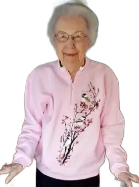 Woman wearing glasses and a pink sweatshirt with a bird and flower design, smiling.