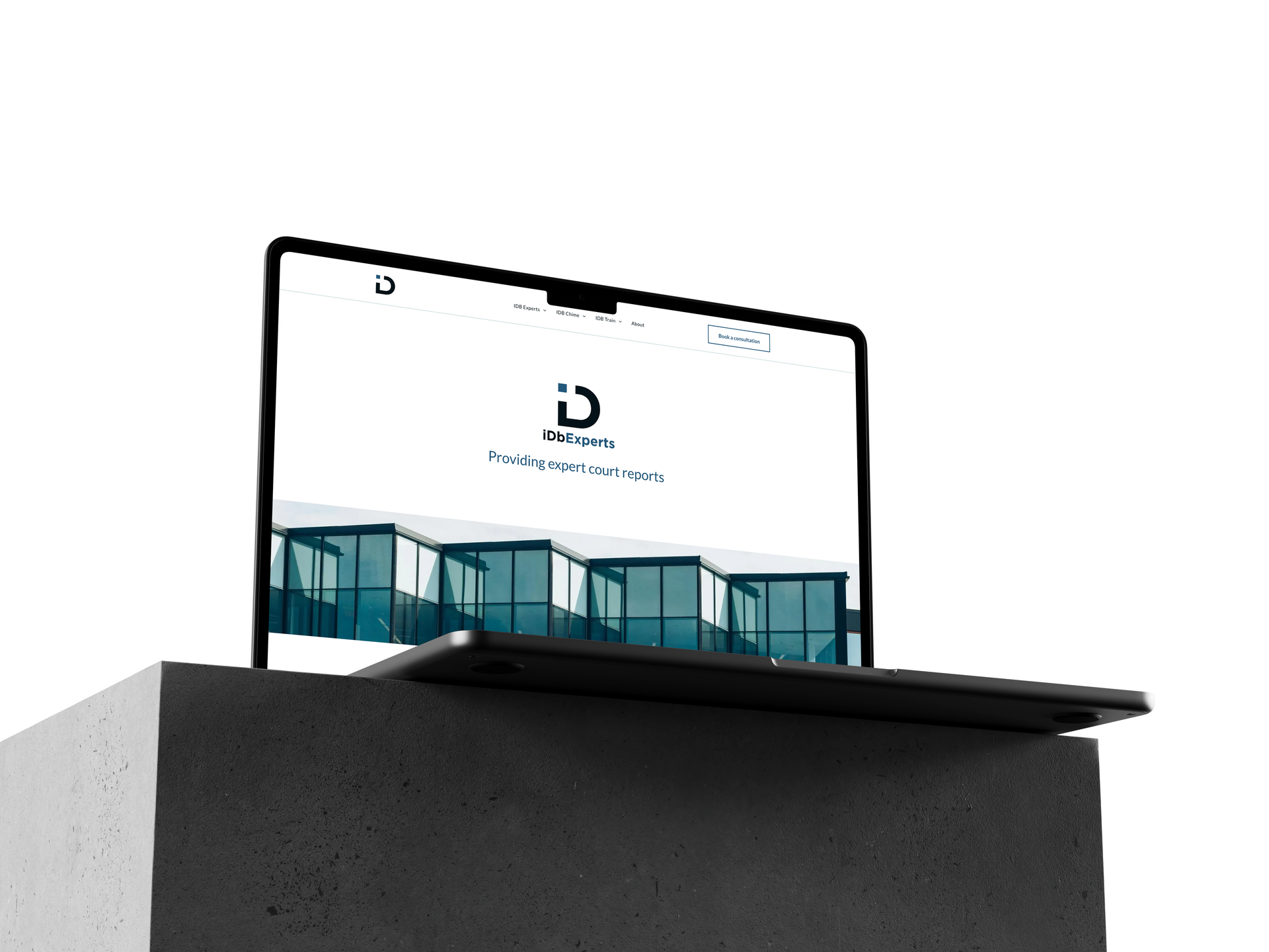 Laptop displaying a website on a concrete surface against a white backdrop.