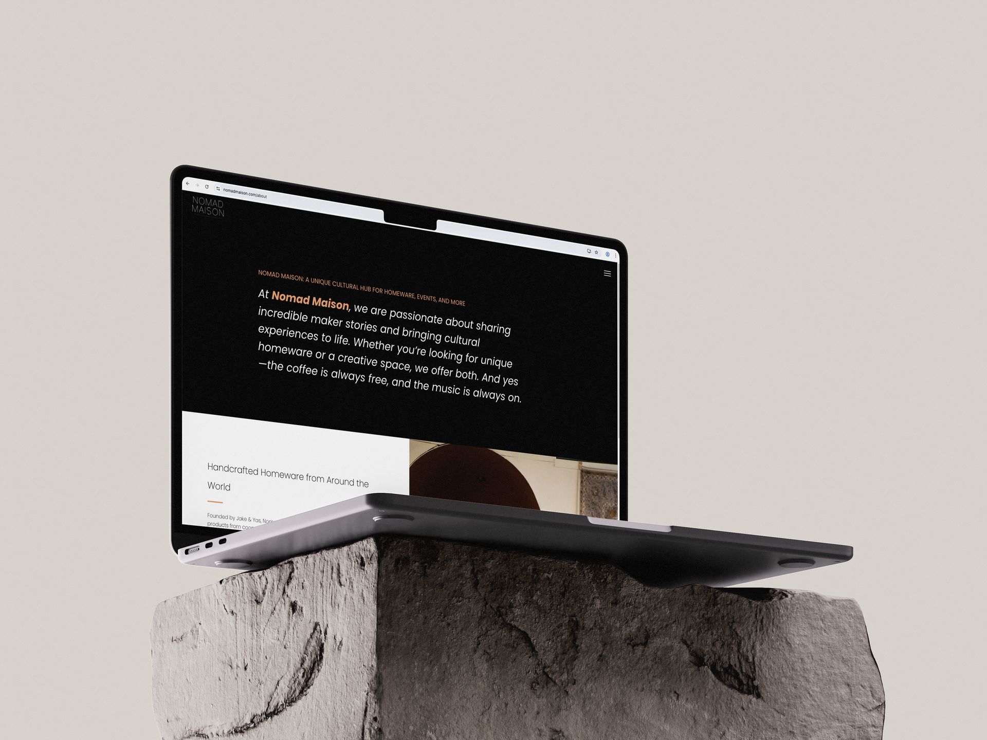 Laptop on a concrete block, website visible on screen. Beige background.