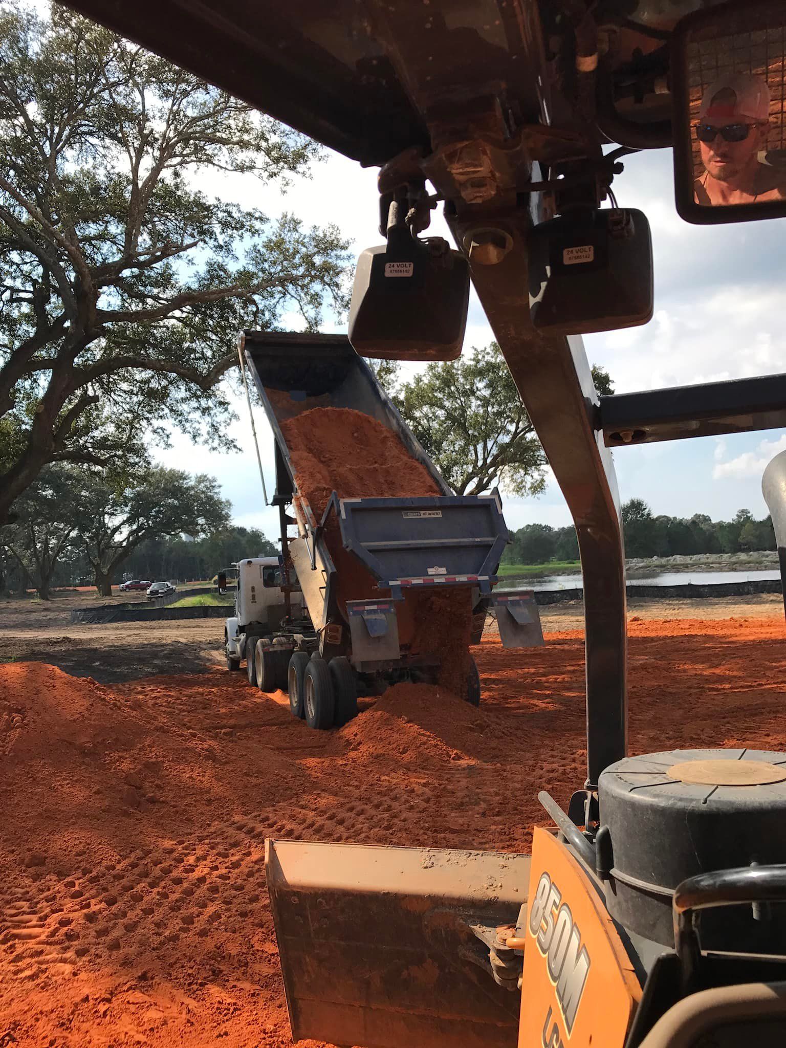 A dump truck is being loaded with dirt on a construction site.