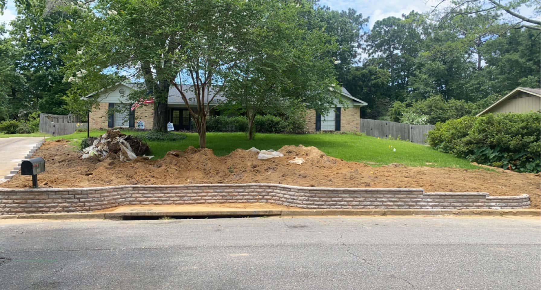 A brick wall is being built in front of a house.