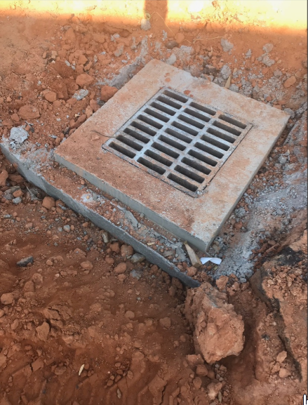 A manhole cover is sitting on top of a pile of dirt.