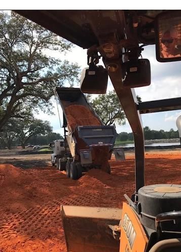 A bulldozer is working on a dirt road in the woods