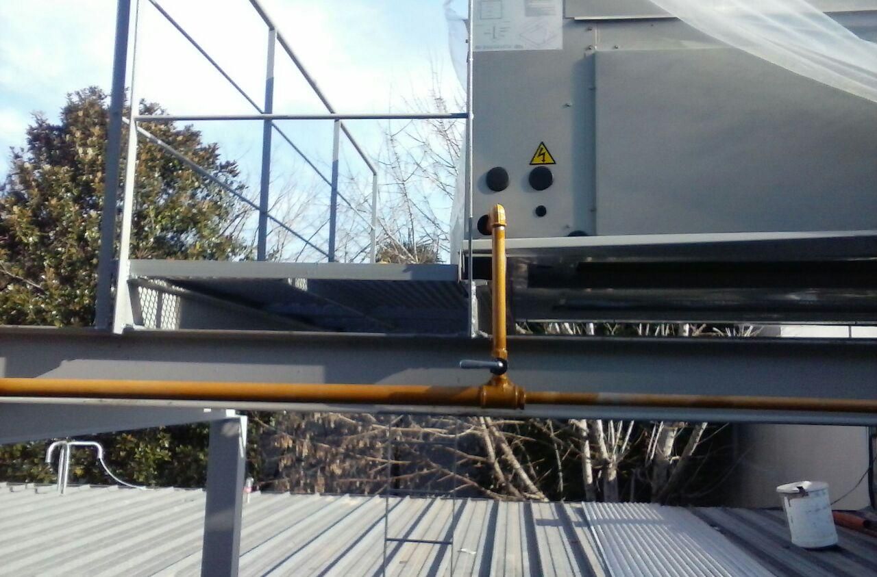 Interior de un centro comercial de varios niveles con atrio y escaleras mecánicas. Arquitectura beige y marrón, gente caminando.
