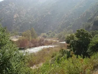 Tree Removal Service West Covina River flowing through a valley surrounded by lush green hillsides on a hazy day.