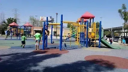 Tree Removal Service West Covina Children play on a brightly colored playground with slides, swings, and climbing structures on a sunny day.