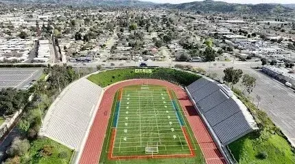 Tree Services West Covina - Aerial view of a football stadium with a track and bleachers, overlooking a residential neighborhood.