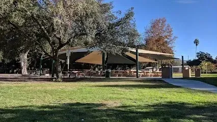 Tree Services West Covina - Picnic tables and benches are set up under large shade structures in a park on a sunny day.