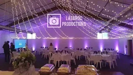 Tree Removal Service West Covina highlighting an indoor event setup with round tables, white chairs, purple up lighting, and string lights hanging from the ceiling, creating a festive and elegant atmosphere.