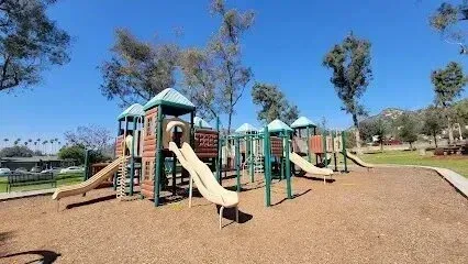 Tree Removal Service West Covina -Colorful playground equipment with slides and climbing structures sits under a bright blue sky.