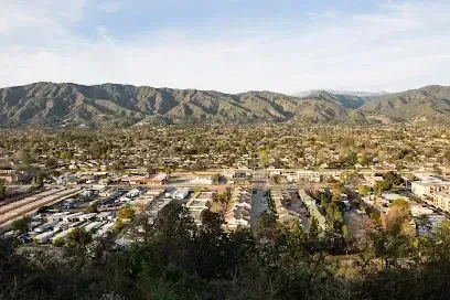 Tree Services West Covina - Panoramic view of a suburban town nestled at the base of rolling green mountains.