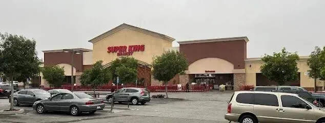 Tree Services West Covina - Super King Market storefront with a parking lot full of cars and trees under a cloudy sky.