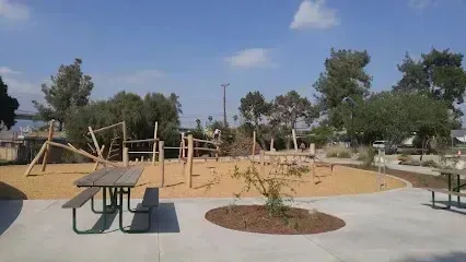 Tree Removal Service West Covina Wooden climbing structures and a picnic table in a sunny park with trees and a bright blue sky.
