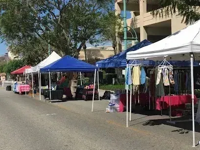 Tree Removal Service West Covina Outdoor market stalls line a street with various vendors selling clothing and other goods under canopies.