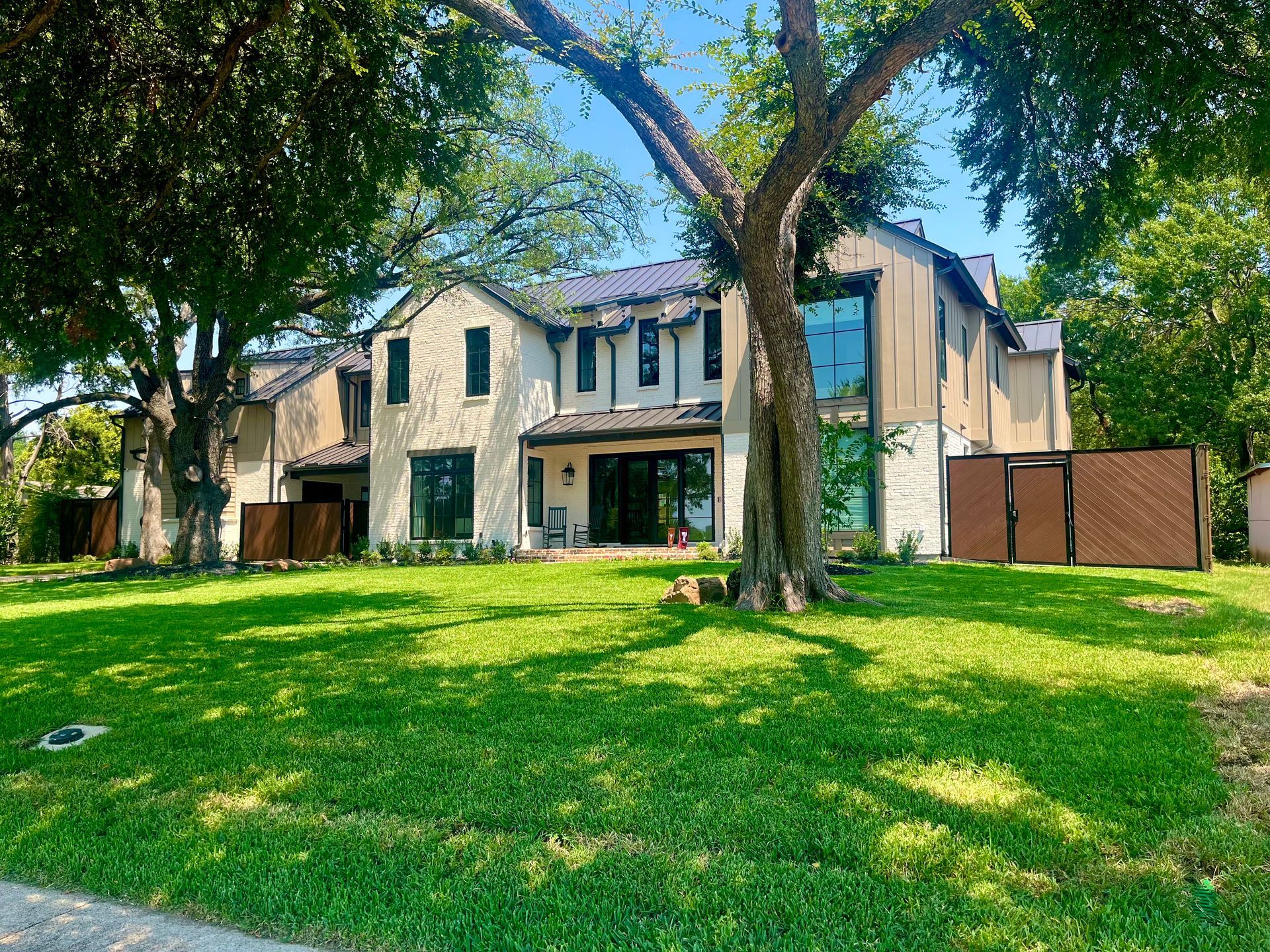 A large house with a driveway leading to it is surrounded by trees.