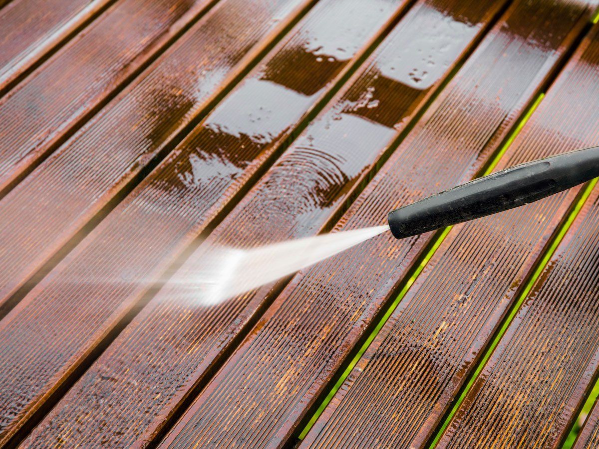 Closeup View of Using Pressure Washer to Clean Wood Terrace — Hayward, WI — Schobert’s Painting & Decorating LLC