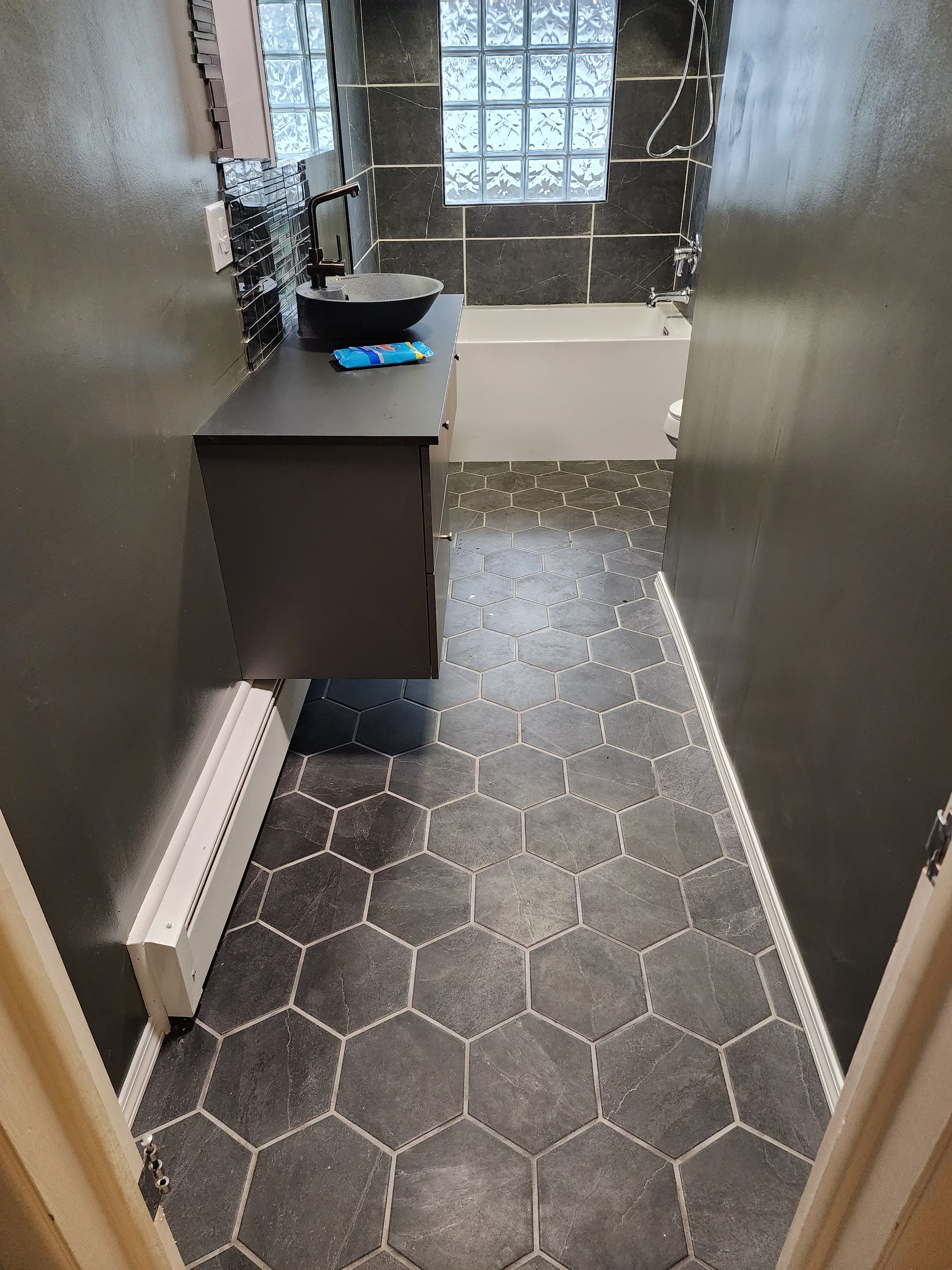A bathroom with a sink , tub and mirror.