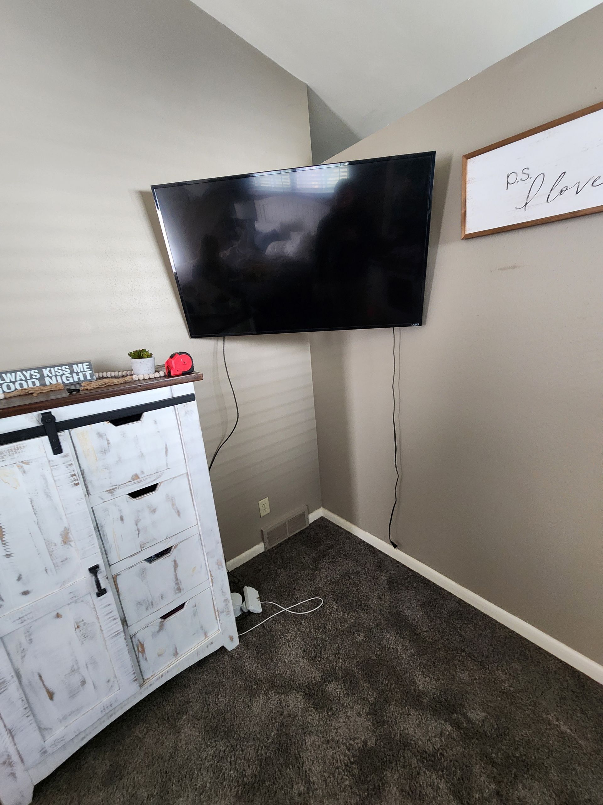 A room with a dresser and a flat screen tv on the wall.