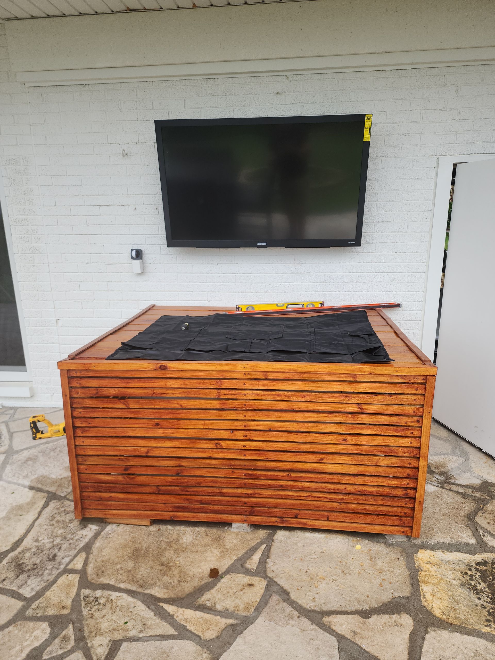 A large flat screen tv is mounted on the wall above a wooden box.