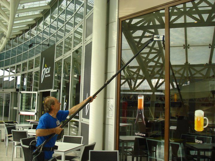 Un uomo sta pulendo la finestra di un ristorante con un lungo palo