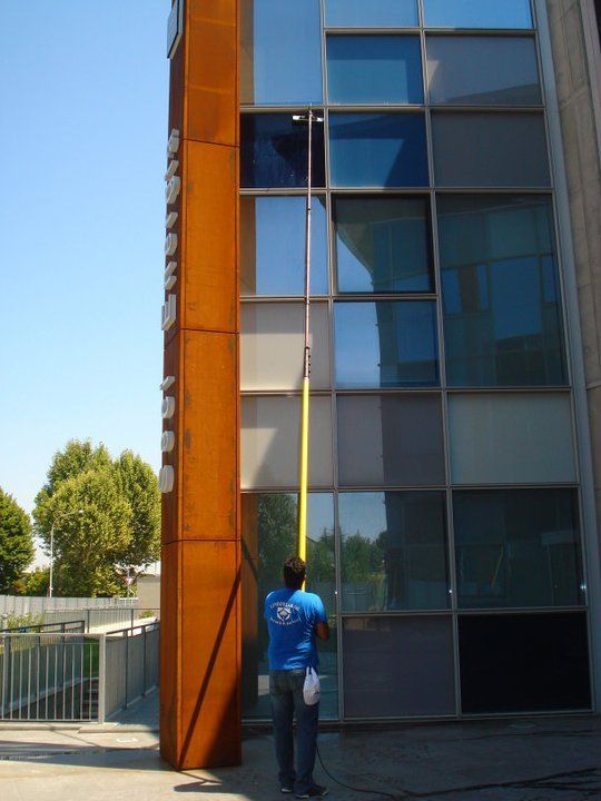 Un uomo con una camicia blu sta pulendo le finestre di un edificio