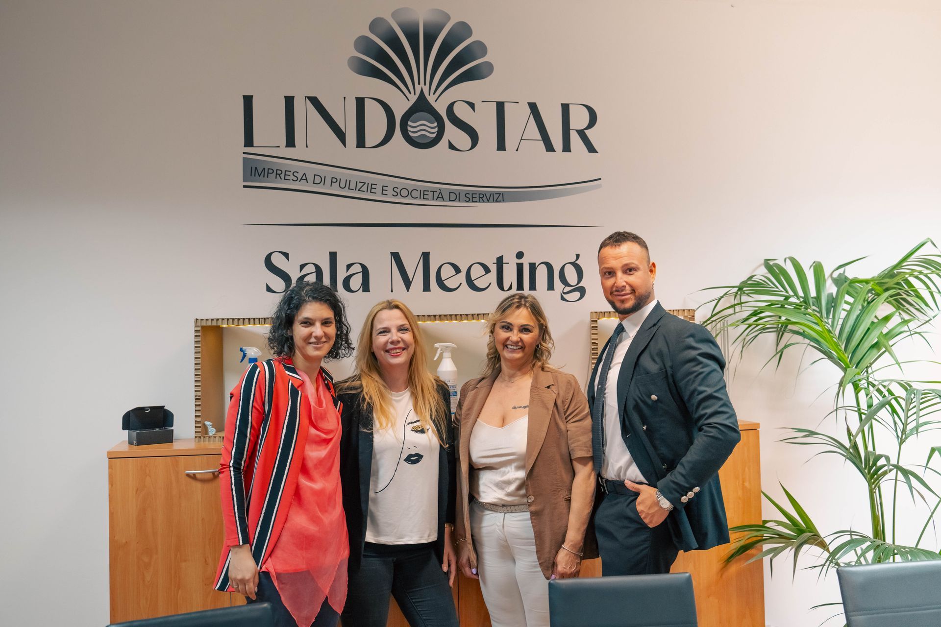 Due donne si stringono la mano davanti a un logo blu e bianco