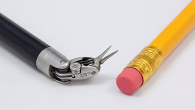 Instrumento cirúrgico com uma tesoura pequena ao lado de um lápis amarelo com uma borracha rosa.