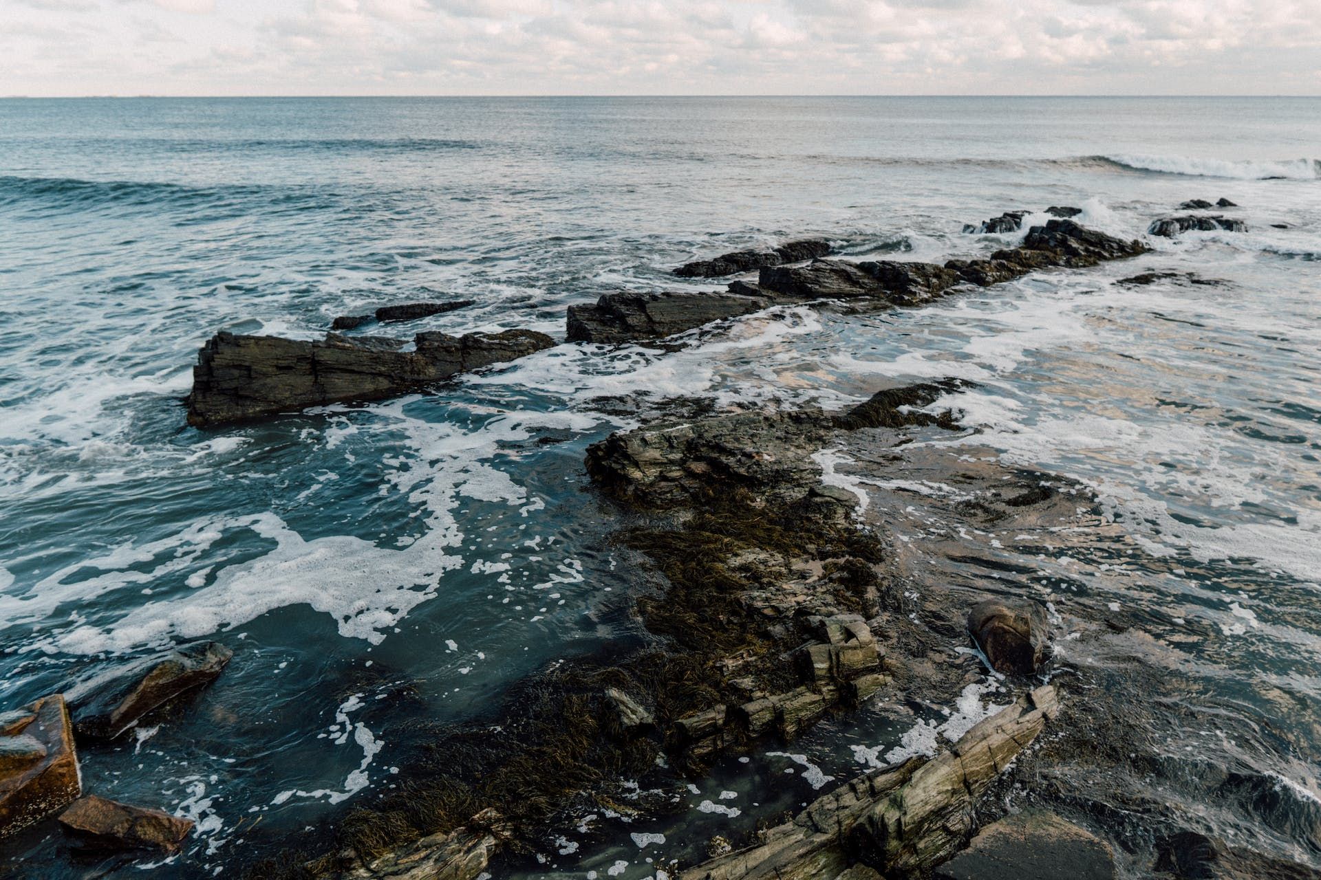 A rocky shoreline of the ocean with waves crashing against the rocks.