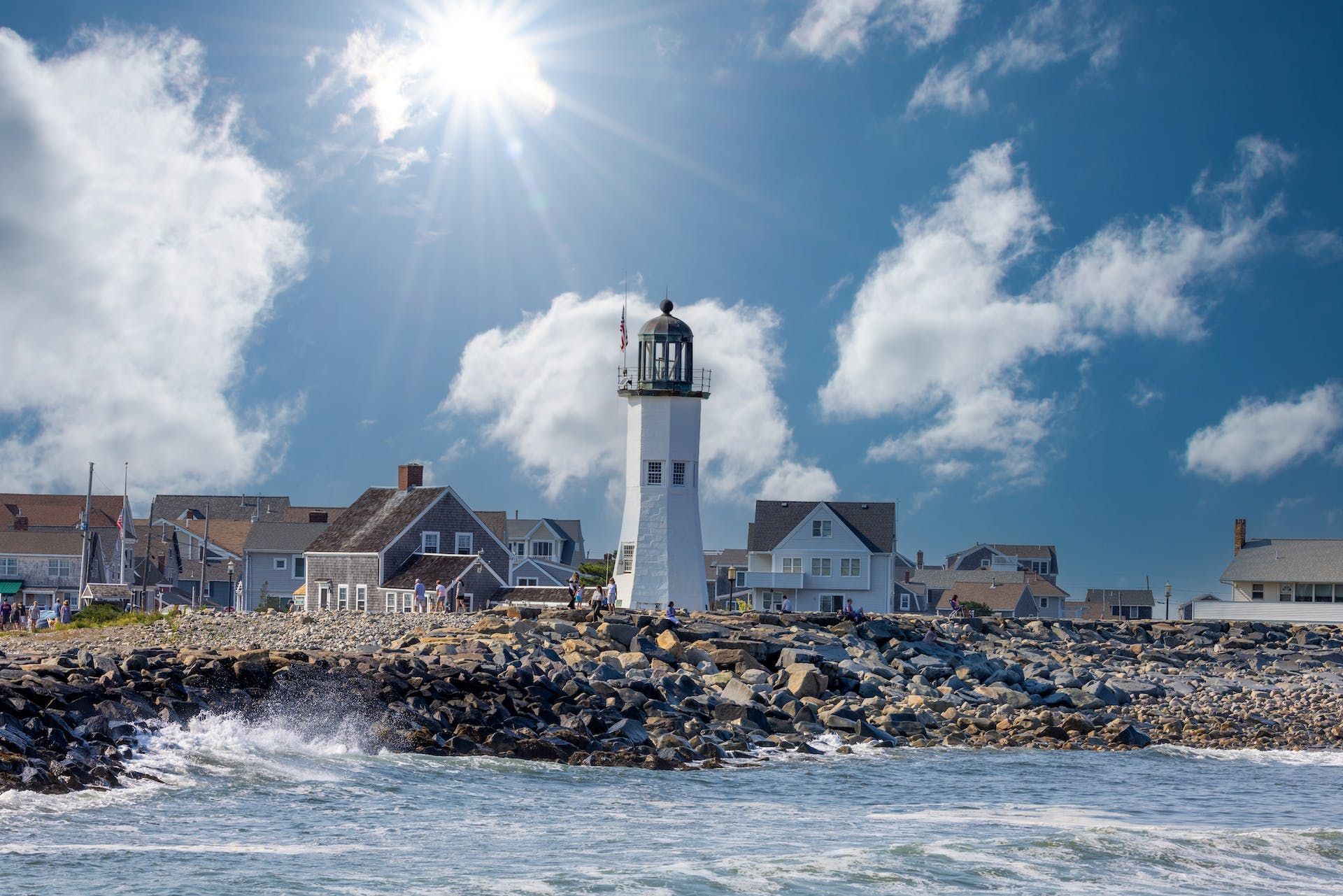 A lighthouse is sitting on top of a rocky hill next to the ocean.