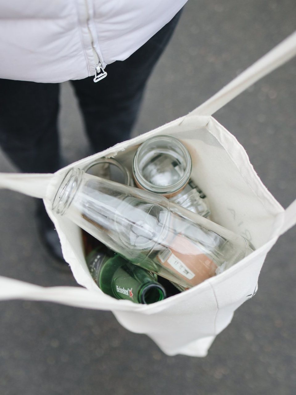 A person is carrying a bag full of empty bottles and glasses