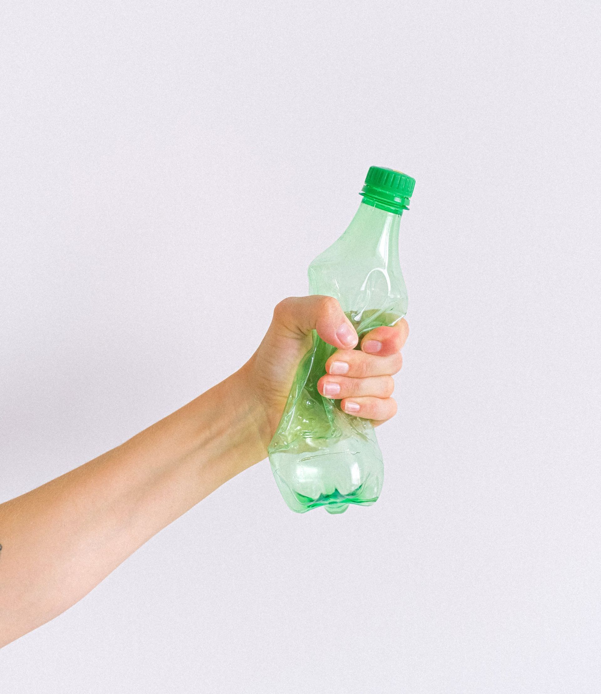 A person is holding a green plastic bottle in their hand.