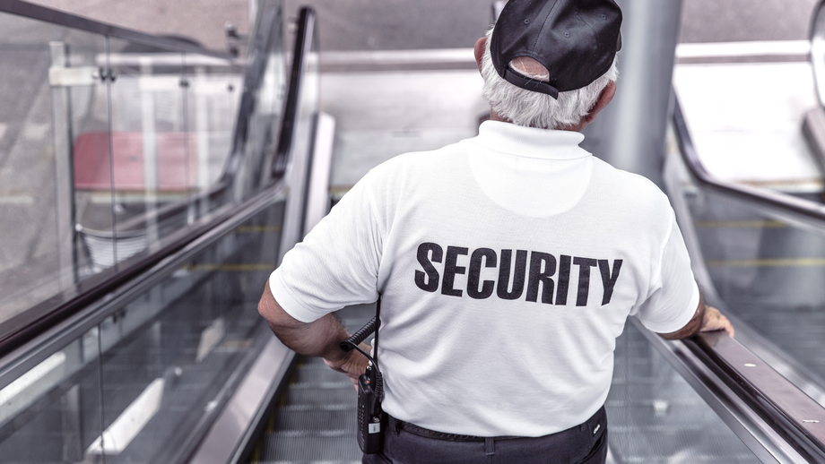 Security guard on an escalator, wearing a white shirt with