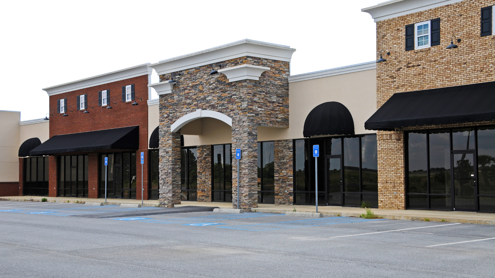 Empty commercial storefronts with glass windows, brick and stone facade.