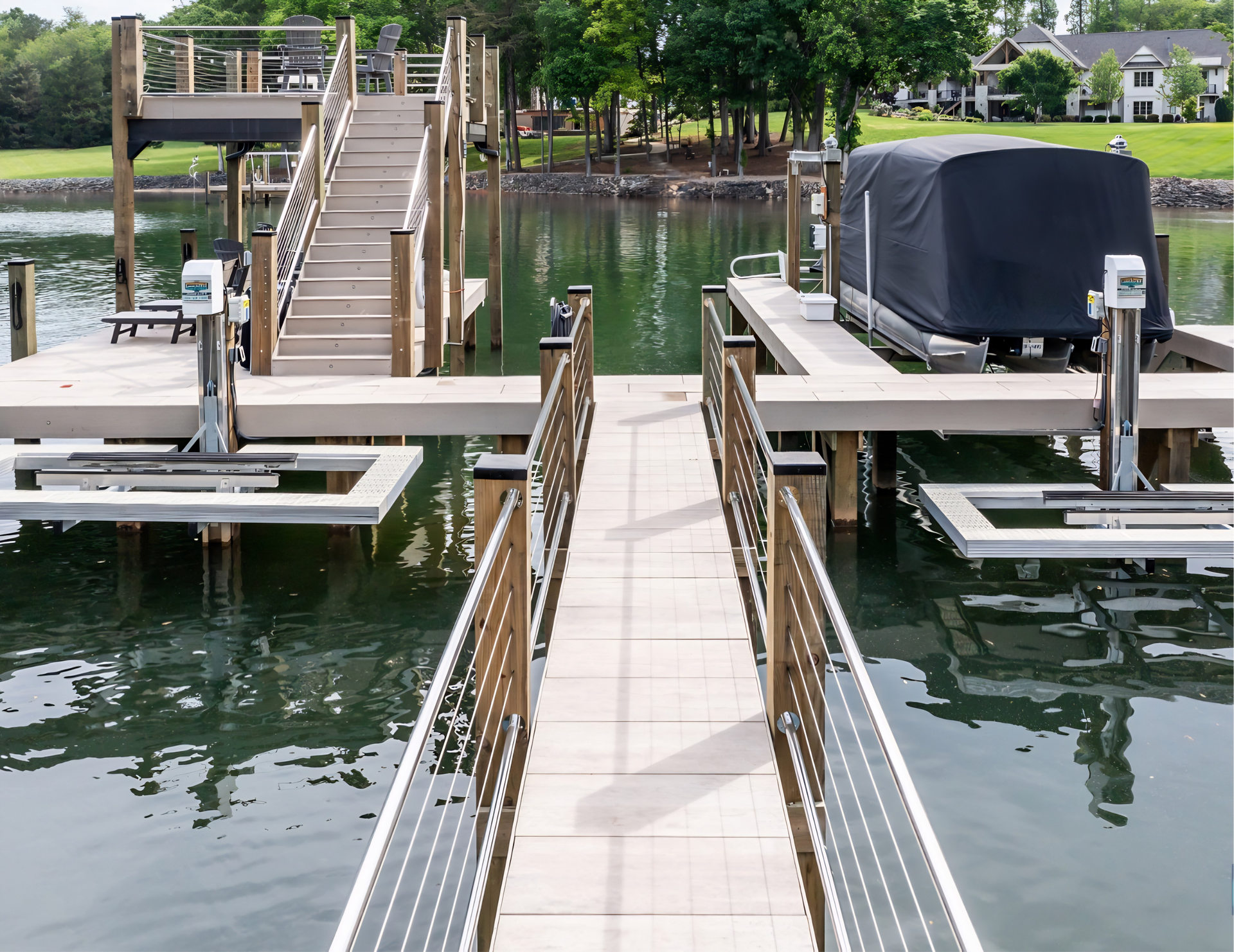 Wooden dock walkway between two boat lifts on a calm lake, with stairs and railings ahead