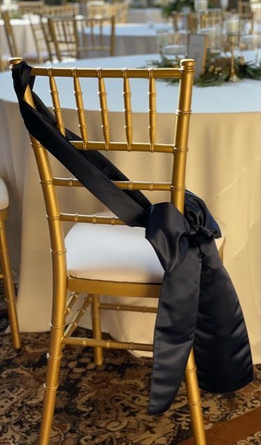 A row of gold chairs with white cushions are lined up in front of a window.